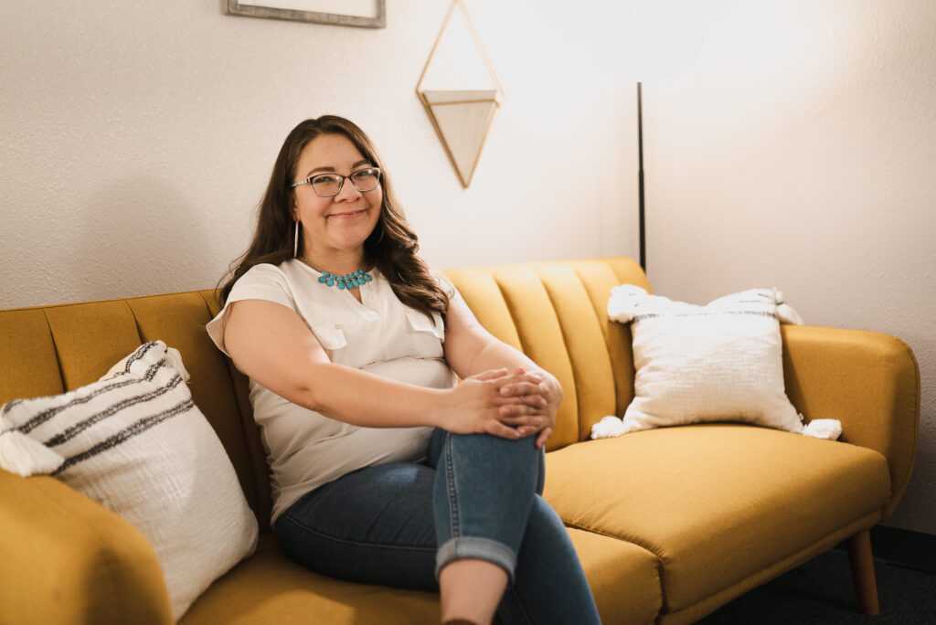 FYI+ La terapeuta Maria Brady sentada en un sofá amarillo